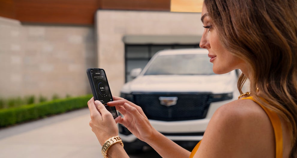 lady checking her mobile with a Cadillac vehicle background | Swickard Cadillac of Thousand Oaks in Thousand Oaks CA